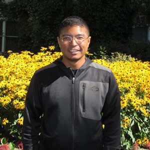 Picture of Jacob Bostick near yellow flowers.